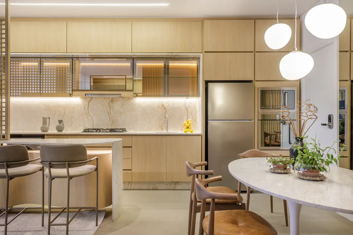 Apartamento decorado do Réve: cozinha com revestimento em pedra, marcenaria clara e mesa de jantar oval