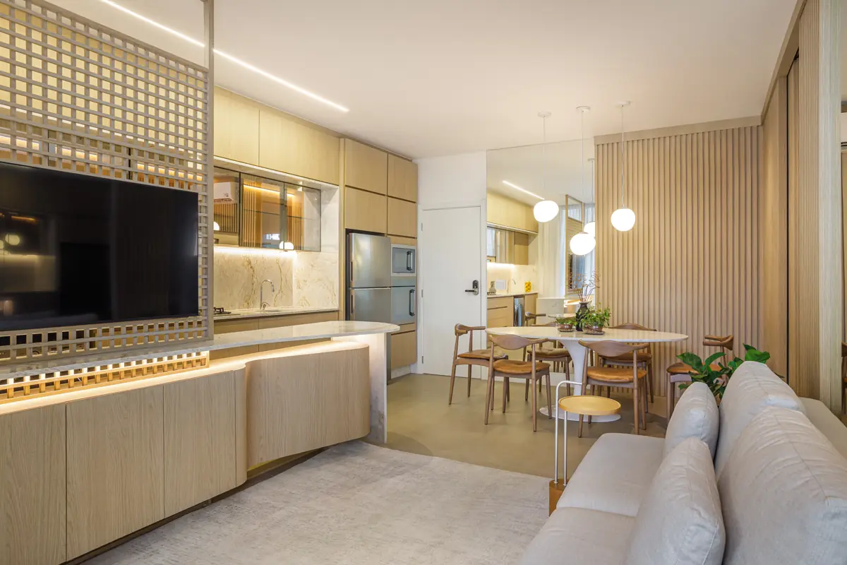 Apartamento decorado do Réve: sala com divisória em treliça de madeira, TV e cozinha ao fundo