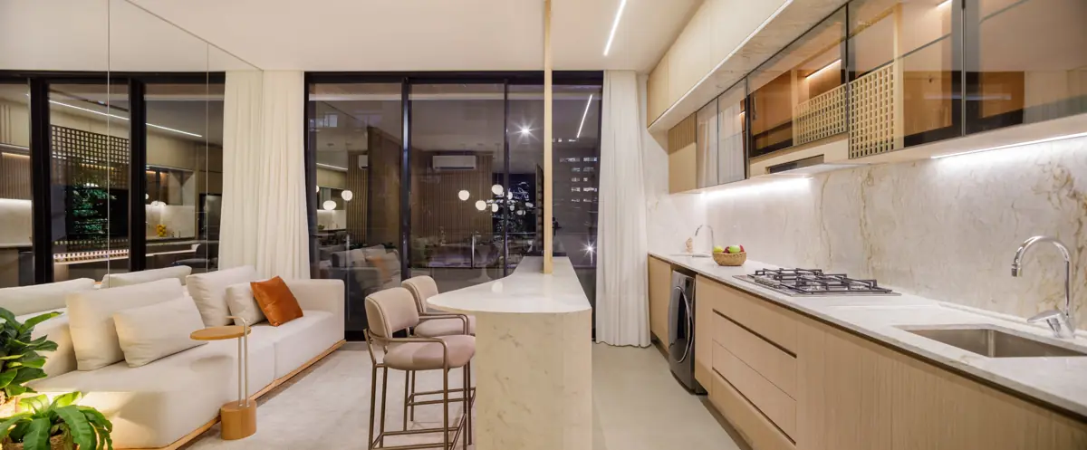 Apartamento decorado do Réve: sala de estar integrada à cozinha, com bancada em pedra clara e esquadrias amplas
