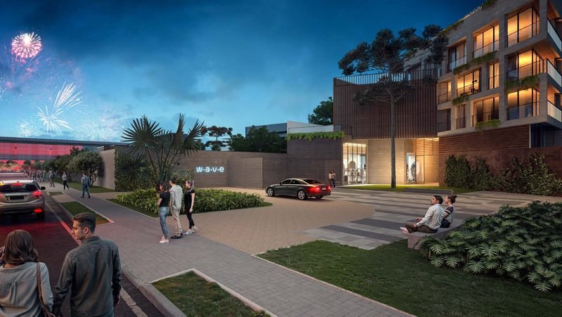 Fachada do Wave Lofts ao anoitecer, com porte-cochère, jardim e janelas iluminadas
