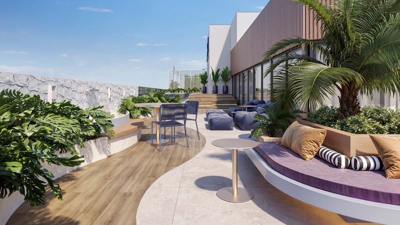 Lounge externo do rooftop com sofás, plantas e piso de madeira